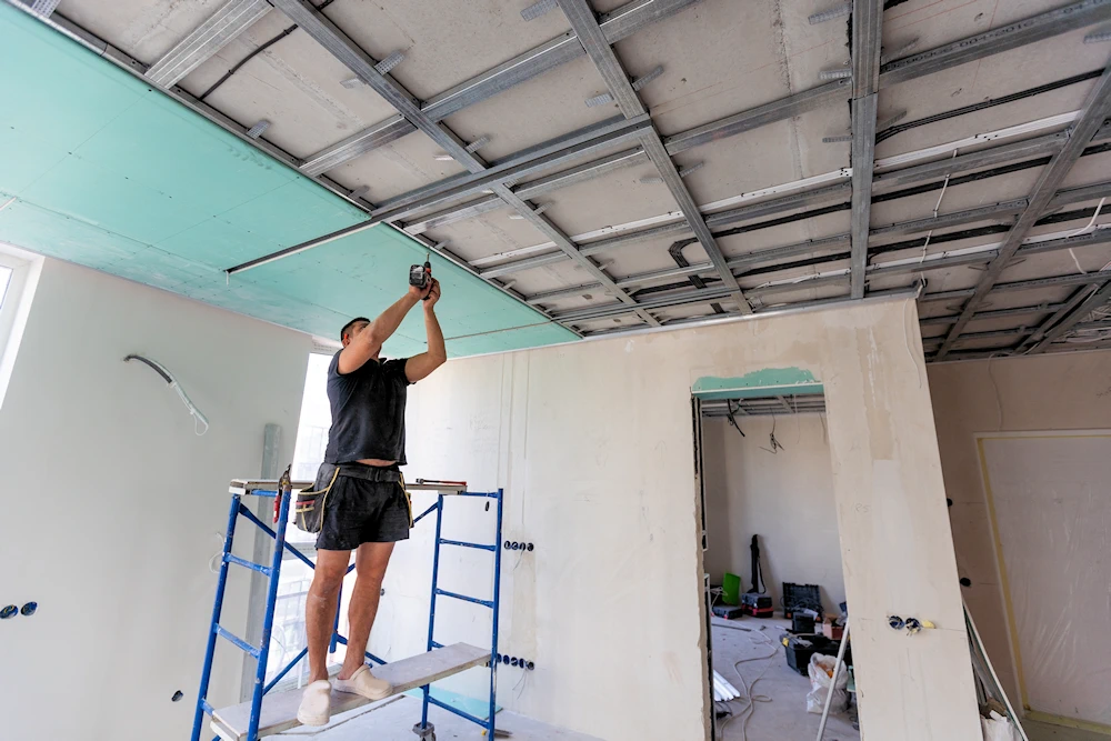 Worker hanging drywall on the ceiling